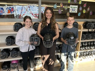 Rimbey Elementary School Admin Assistant Bre Button (centre), with students Josie Beagle (left, Grade 5) and Blake Hetherington (right, Grade 6), shows off some of the new hockey helmets purchased with a $5,000 Hockey Alberta grant, helping ensure student