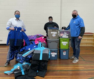Ponoka Elementary School (PES) principal Nathan McEntee, accepts a donation of winter wear from Halla Letendre and Pastor Rob McArthur from Home Church Ponoka, Nov. 17. Members of Home Church donated $2,500 worth of winter clothing for PE
